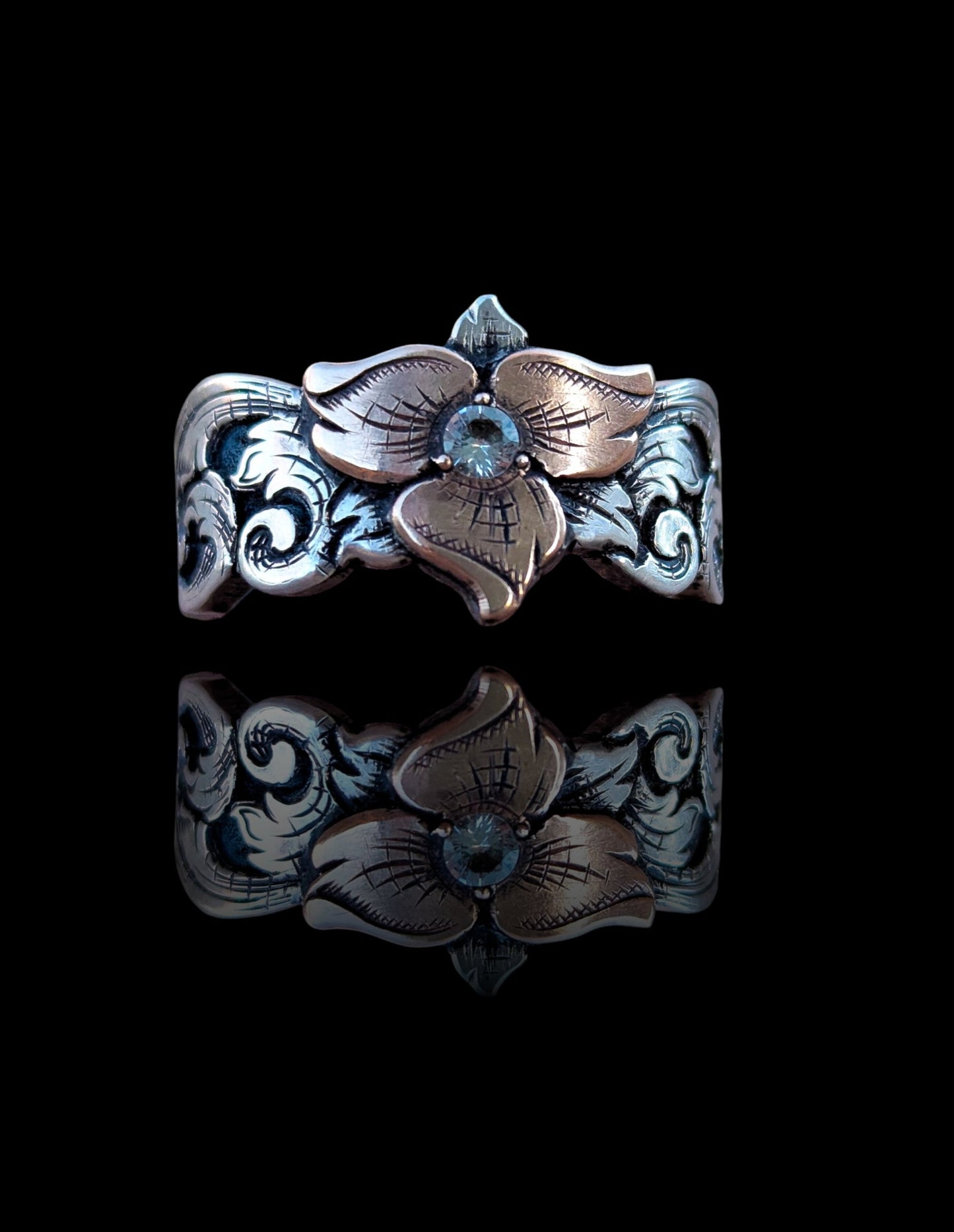 Silver ring with floral design on a black background